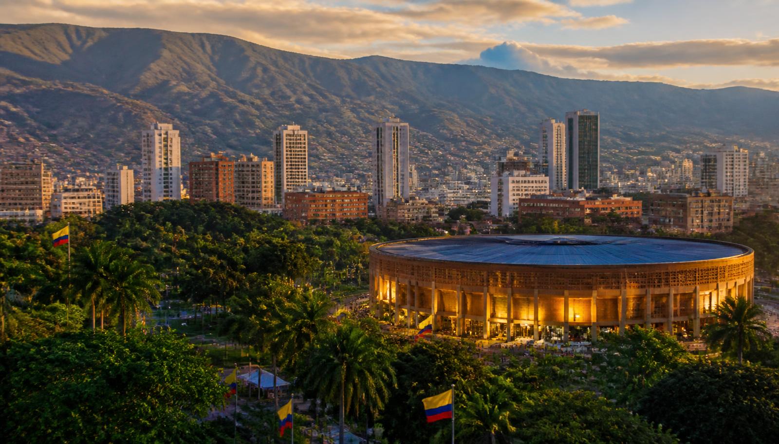 Panorámica de Cali con una gran arena iluminada al atardecer, sede propuesta de la posesión presidencial