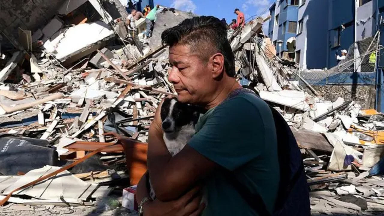 Hombre damnificado abraza a su perro frente a los escombros de un edificio colapsado tras el terremoto en Colombia