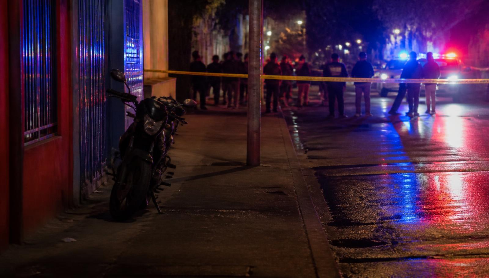Calle de Cali de noche con luces de patrulla de policía y una motocicleta detenida