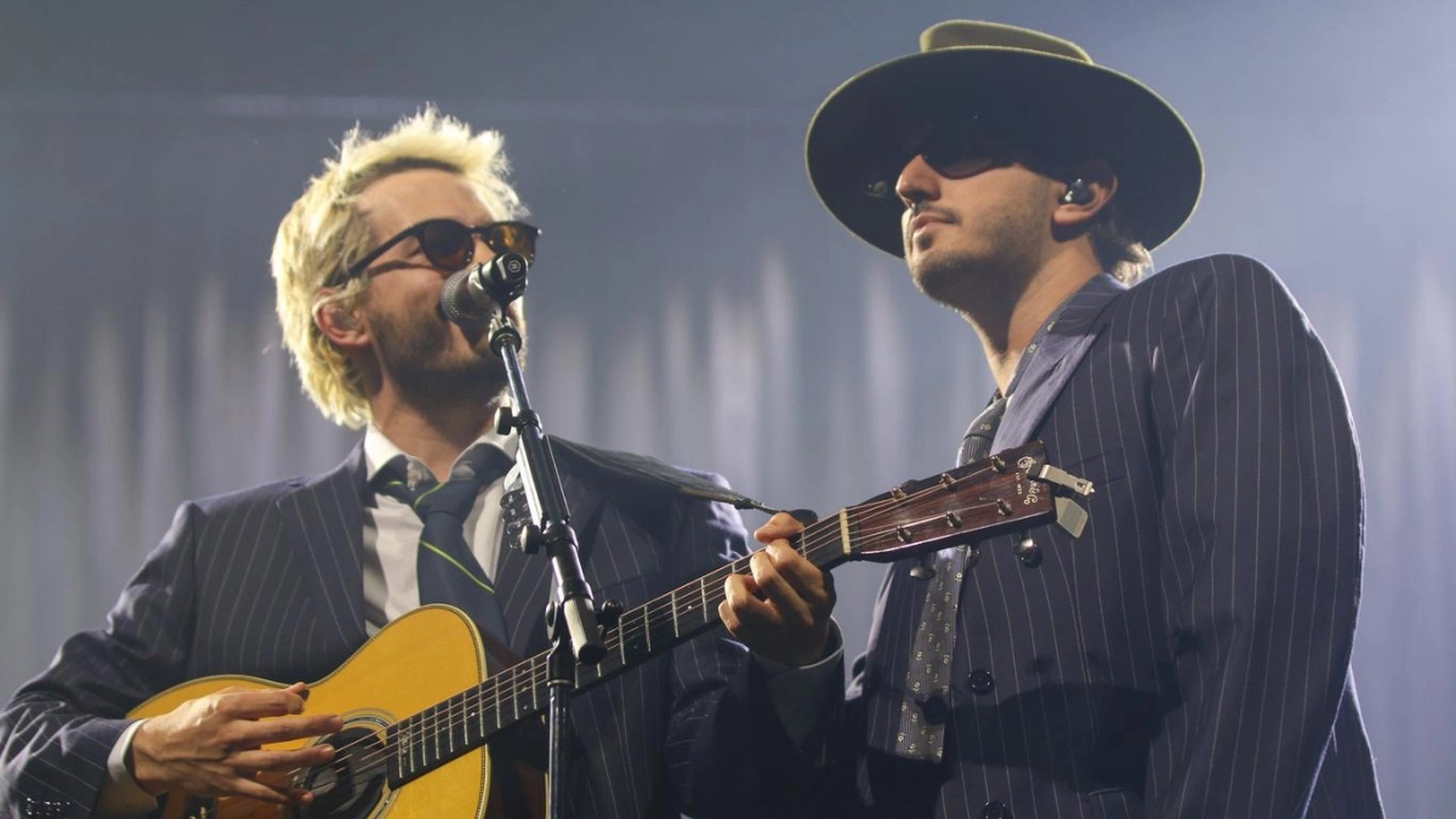 Dos músicos cantan sobre el escenario durante un concierto